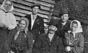 Famille posant devant une maison en bois. Les femmes portent des foulards, les hommes des chapeaux. Un nom de famille slovaque pourrait être associé à cette photo d'ancêtres.