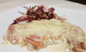 Deliziosa cotoletta alla bolognese, dorata e ricoperta da una cremosa salsa, accompagnata da radicchio croccante.