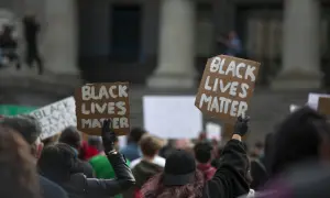 Ludzie protestują przeciwko rasizmowi, trzymając transparenty "Black Lives Matter".
