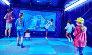 Kinder haben Spaß bei interaktiven Veranstaltungen in Berlin. Sie springen und spielen vor einer großen Leinwand mit einem Fußballspiel.