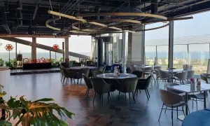 Eleganckie wnętrze restauracji Olivia Star z widokiem na miasto i morze. Stoły nakryte, gotowe na przyjęcie gości.