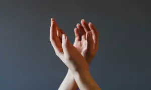 Dłonie splecione w geście, który może symbolizować trudności w wyrażaniu emocji, ale też potencjał do rozwoju psychomotoryki.