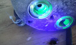 Détection de fuite climatisation voiture : le traceur fluorescent vert révèle une infiltration dans le compresseur.