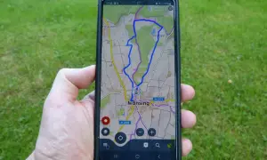 Hand hält Smartphone mit einer Wanderwege App, die eine Route bei Munsing anzeigt. Perfekt für die nächste Tour!