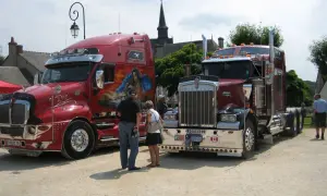 Deux camions américains tuning, l'un rouge vif avec une peinture personnalisée, l'autre bordeaux, se dressent fièrement.