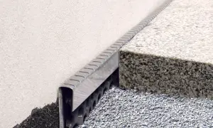 Noppenbahn mit Bitumen kleben: Detailaufnahme einer Fassadenabdichtung mit Drainageschicht und Granitstufe.