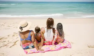 Rodzina cieszy się wspólnym weekendem z dzieckiem na plaży, patrząc na fale oceanu.