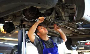Mechanik dokonuje wymiany tulei wahacza, pracując pod podniesionym samochodem.