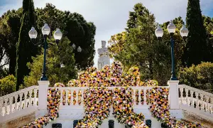 Escaleras adornadas con miles de flores vibrantes, donde zgz florece en un espectáculo de color. Una estatua real preside la escena.
