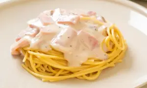 Pyszny makaron z serem i kawałkami szynki w kremowym sosie.