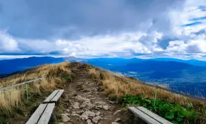 Kamienista ścieżka prowadzi na szczyt, skąd roztacza się widok na Bieszczady. W oddali widać kolejne pasma górskie.