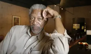 Morgan Freeman młody, z siwą brodą i zmarszczkami, opiera głowę na dłoni.