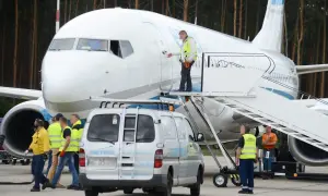 Pracownicy lotniska przygotowują samolot do lotów z Babimostu. Widać schody, furgonetkę i personel w kamizelkach odblaskowych.