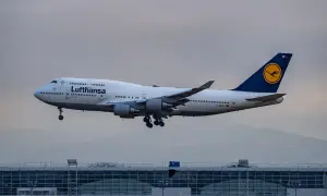 Lufthansa Boeing 747 im Landeanflug über einem modernen Flughafengebäude.