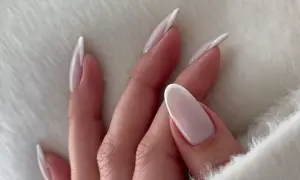 Dłonie z mlecznymi paznokciami w stylu french manicure, delikatne i eleganckie.