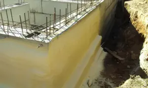 Izolacja fundamentów w starym domu w trakcie prac. Betonowe ściany zbrojone, gotowe do dalszych etapów budowy.