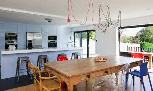Un affascinante abbinamento sedie Kartell con tavolo antico in legno, circondato da una cucina moderna e un giardino lussureggiante.