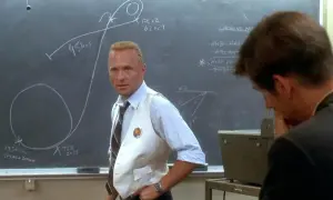 Gene Kranz, w białej kamizelce, omawia trajektorię misji Apollo 13 na tablicy.
