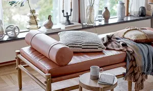Un cómodo espacio de meditación con un banco de cuero, cojines texturizados y mantas cálidas.