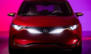 Czerwone izera auto z nowoczesnymi światłami LED i logo producenta na tle fioletowo-różowego oświetlenia.