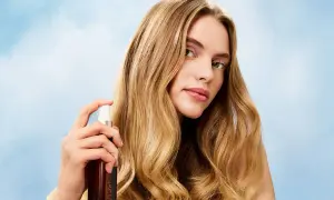 Mujer rubia aplica bruma en su pelo, logrando un brillo radiante.