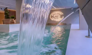 Cascada de agua en piscina interior, con iluminación circular y zona de descanso. Un oasis de spa sol y mar en Calpe.