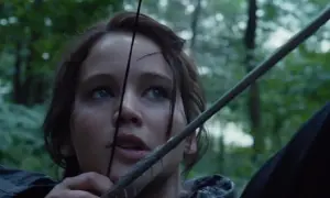 Katniss Everdeen siktar med pilbåge i skogen, redo för hunger games ordning.
