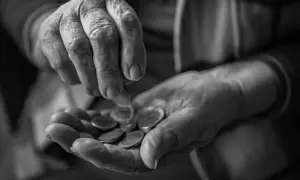 Mani anziane contano monete, un gesto che evoca la domanda su a quanto ammonta l'assegno di accompagnamento.