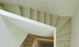 Escalera moderna de diseño minimalista con revestimiento blanco y peldaños de madera clara.