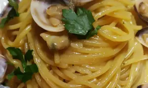 Spaghetti alle vongole cremosi come al ristorante, un piatto invitante con pasta dorata, vongole succulente e prezzemolo fresco.