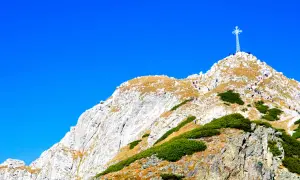 Giewont z Zakopanego, majestatyczny szczyt z krzyżem, na który wspina się grupa turystów.
