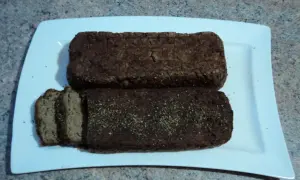 Dwa bochenki domowego pasztetu z kaczki, jeden pokrojony w plastry, na białej tacy.