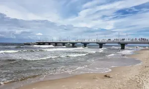 Kołobrzeg wczasy z wyżywieniem: spacer po molo, fale na plaży i tłumy turystów. Idealne miejsce na relaks nad Bałtykiem.