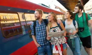 Grupa przyjaciół z mapą przy pociągu, zastanawia się, gdzie na majówkę pociągiem.