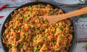 Herzhafte hackfleisch reis pfanne mit Erbsen und Paprika, garniert mit Chilischoten. Ein köstliches Gericht für die ganze Familie.