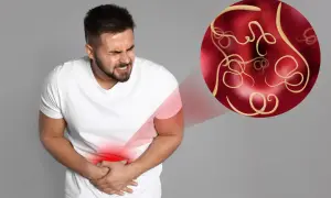 Mężczyzna z bólem brzucha, symbolizującym pasożyty. W okręgu widoczne są robaki, sugerujące pasożyty objawy psychiczne.