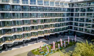 Grupa osób ćwiczy jogę na trawniku przed nowoczesnym seaside park hotel.