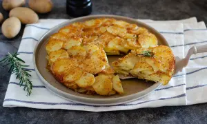 Un delizioso tortino di patate dorato e croccante, servito su un piatto con rosmarino fresco.