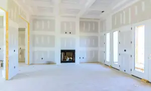 Interno di una casa in costruzione con pareti e soffitti in cartongesso coibentato, camino e porte a doppio battente.