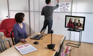 Spotkanie online, gdzie jakość SD a HD robi różnicę. Kobieta patrzy na ekran, mężczyzna pisze na tablicy.