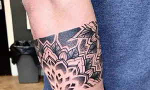 Eleganckie tatuaże męskie na ramieniu w stylu mandali, z motywami liści i geometrycznymi wzorami, wykonane techniką dotwork.