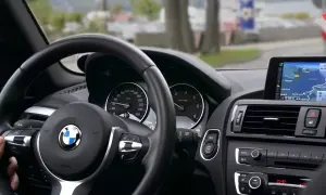 Wnętrze BMW z kierowcą, który zdaje egzamin kontrolny po utracie prawa jazdy za punkty. Nawigacja pokazuje trasę.
