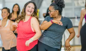 Zwei Frauen lachen und tanzen ausgelassen bei einem Zumba-Kurs. Ein toller Weg, um den **Zumba Kalorienverbrauch** zu steigern und Spaß zu haben!