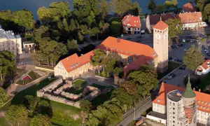 Szczytna atrakcje: ruiny zamku, wieża zegarowa i budynki nad jeziorem.