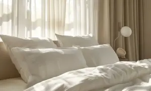 Gemütliches Bett mit weißen Kissen und Decken. Die sanften Falten der Bettwäsche lassen vermuten, dass sie aus einem Material wie Polyester ist, das überraschend warm halten kann.