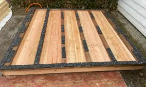 Holzboden für Gartenhaus mit schwarzer Feuchtigkeitssperre am Boden.