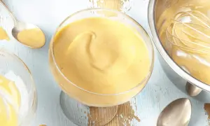 Cremiges Zabaione-Rezept in einem Glas, Löffel daneben. Ein Schneebesen ruht in einer Schüssel mit der köstlichen Masse.