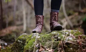Voeten in bruine laarzen op een mosbegroeide steen. Een reflectie van de natuurlijke wereld, misschien een hsp hss test in de buitenlucht.