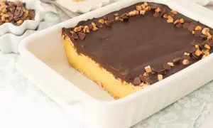 Tarta de natillas y galletas con cobertura de chocolate y trocitos de galleta y chocolate.