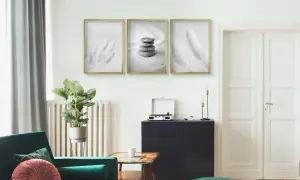 Minimalistyczne plakaty z piórami i kamieniami, zawieszone na ścianie. Idealne do salonu, gdy zastanawiasz się, czym przykleić plakat do ściany.